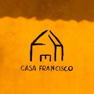 ilustração simples de uma casa centralizada em um fundo amarelo, com o nome do disco logo abaixo